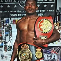 A man holding two boxing belts in his hand.