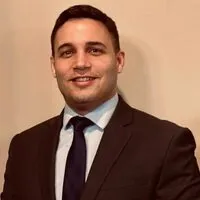 A man in a suit and tie standing next to a wall.