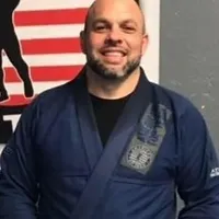 A man in blue and black uniform standing next to an american flag.