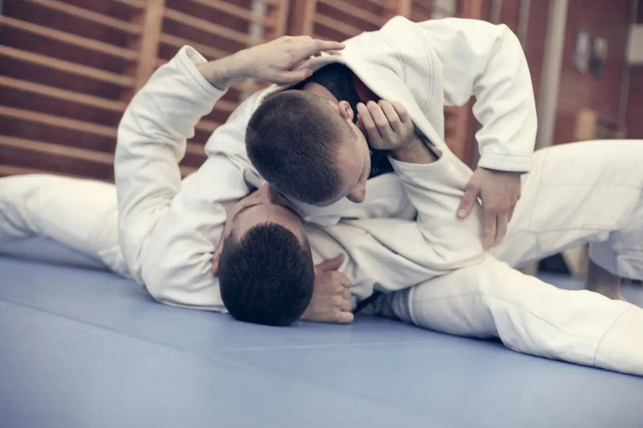 Two men in white uniforms are practicing judo.