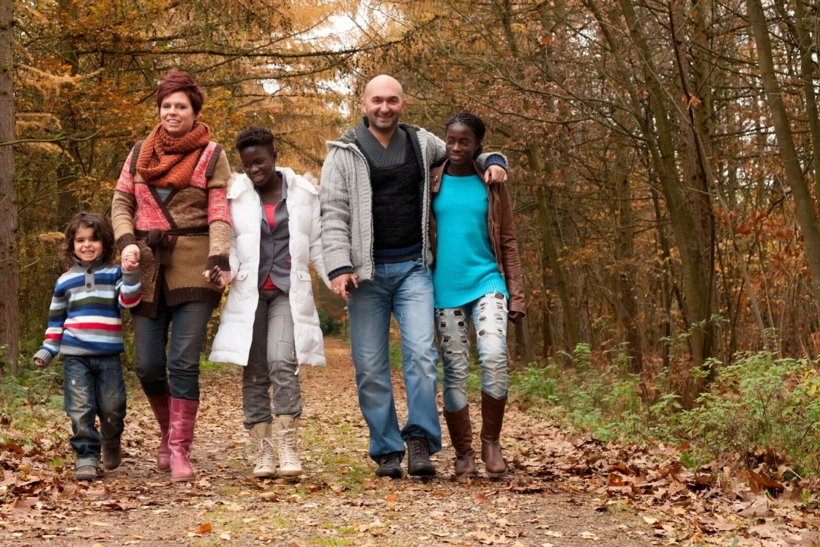 A group of people walking on the trail in the woods.