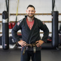 A man in black jacket standing next to a punching bag.