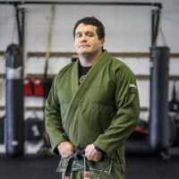 A man in green robe standing next to a punching bag.